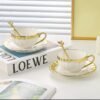Elegant white ceramic cup and saucer set with gold rim accents, classic design, dishwasher and microwave safe